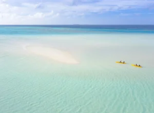 Two people kayaking across the crystal-clear turquoise lagoon in Zanzibar