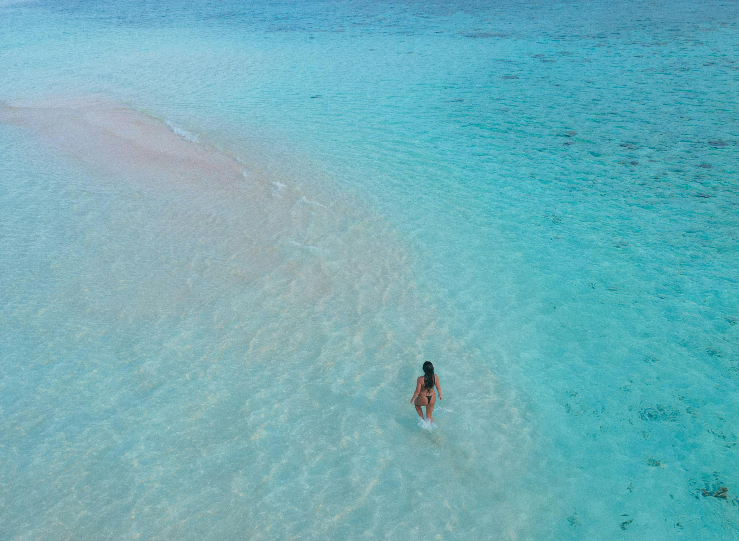 Guest wading through calm turquoise water on a sandbank in Zanzibar