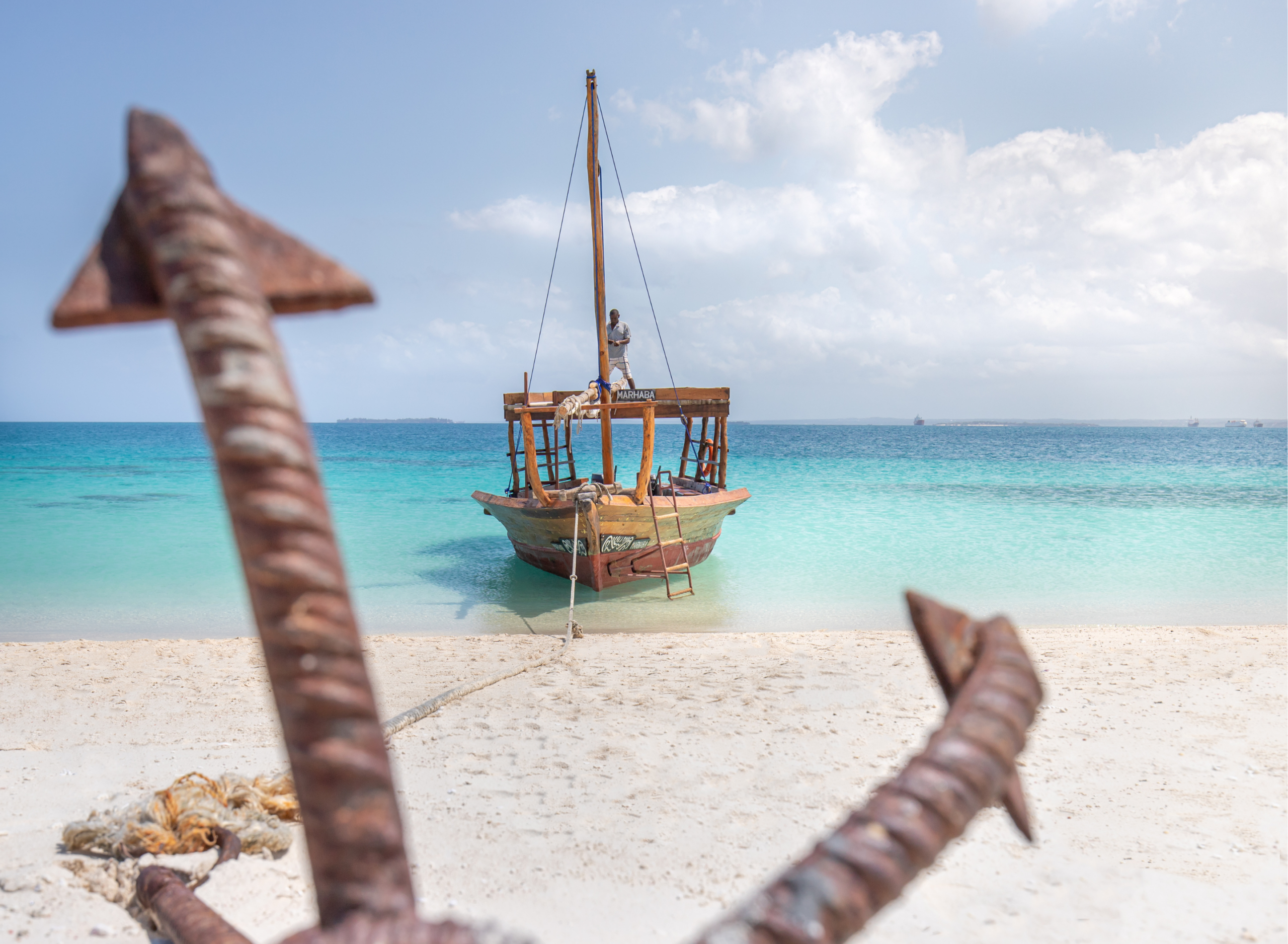 Traditional wooden dhow anchored by a sandy beach in Zanzibar