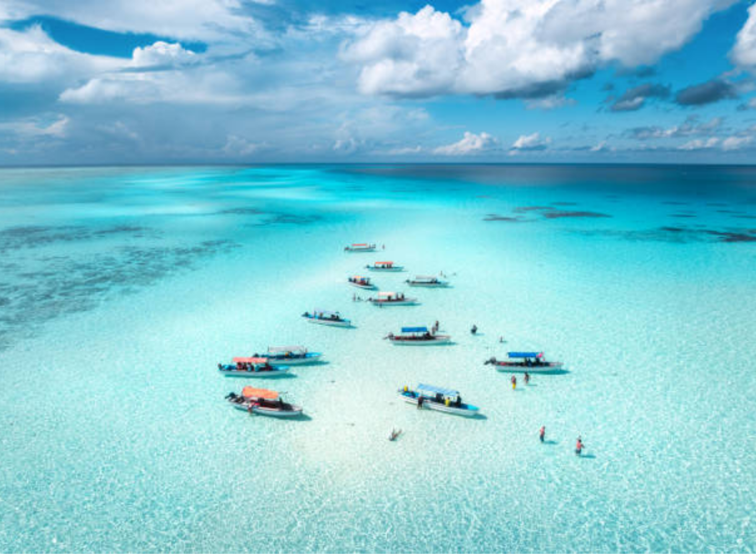 Boats gathered around a white sandbank in turquoise water, Zanzibar